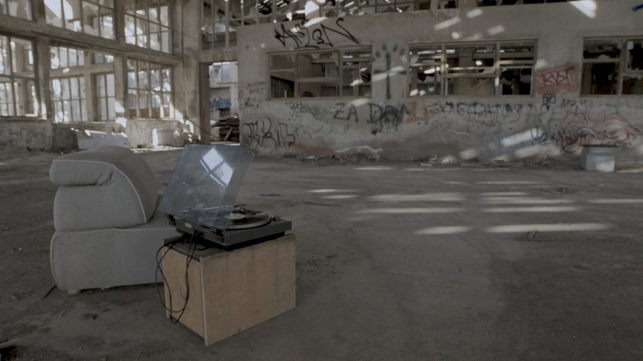 A record player and armchair inside an abandoned industrial building