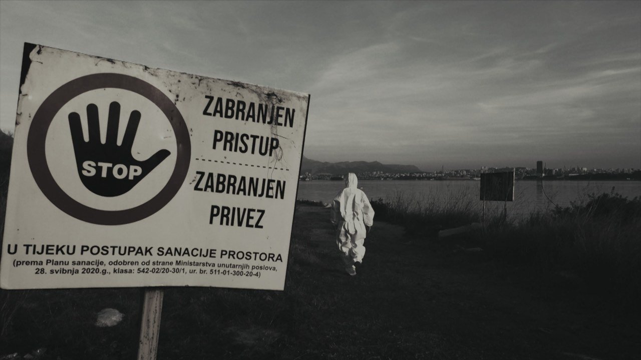 A warning sign beside a figure wearing protective clothing